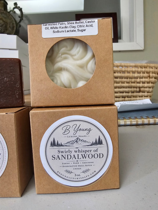 Swirly Whisper of Sandalwood soap visible through a kraft window box above its labeled packaging.