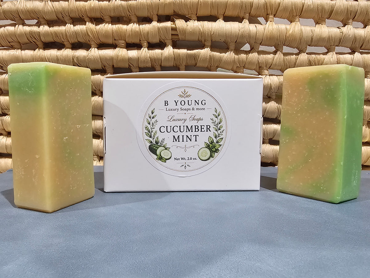 Two green-and-cream Cucumber Mint Goat Milk Soap bars beside their branded white box.